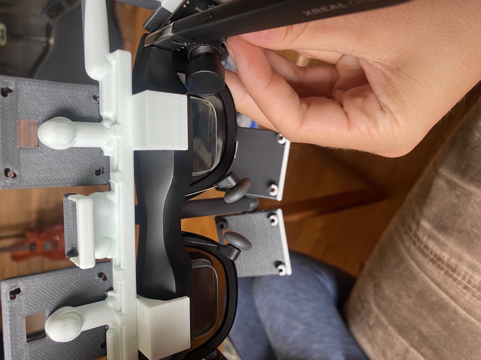 The printed carrier clamped onto the brow of the glasses, held in one hand
