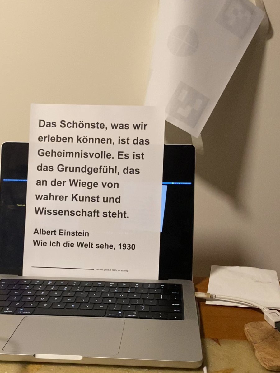 A printed page propped on a laptop with the first two sentences of Einstein's essay Wie ich die Welt sehe in German, signed Albert Einstein, Wie ich die Welt sehe, 1930